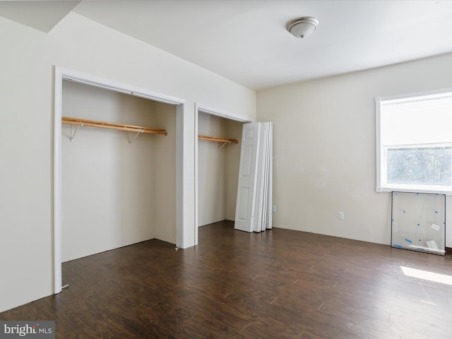 unfurnished bedroom featuring two closets and dark hardwood / wood-style floors