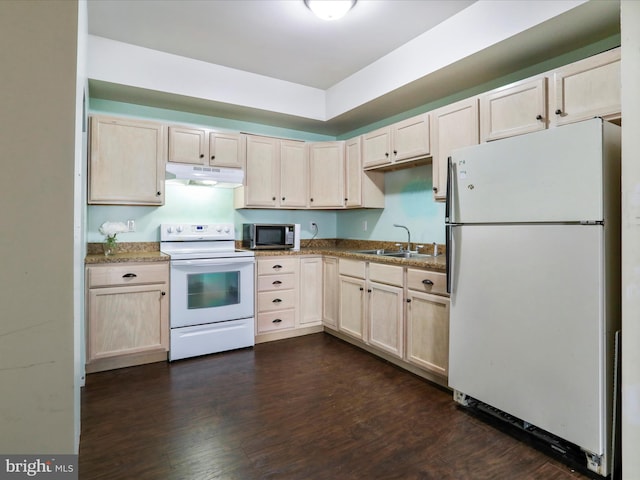 kitchen with white appliances, dark stone countertops, sink, and dark wood-type flooring