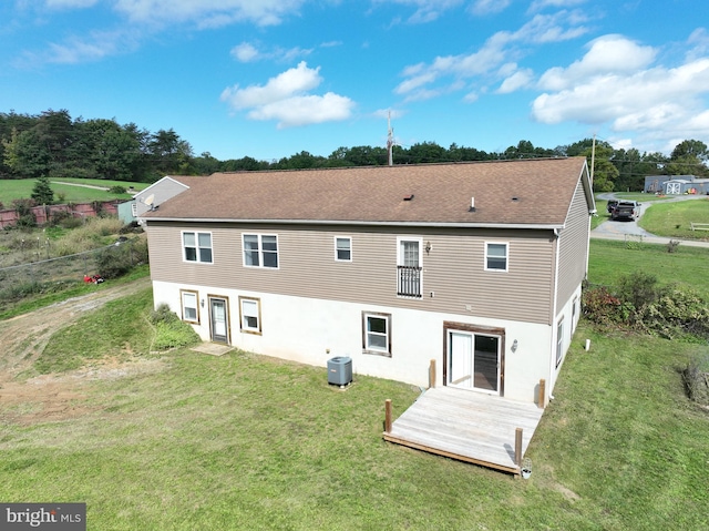 rear view of property featuring central AC unit and a lawn