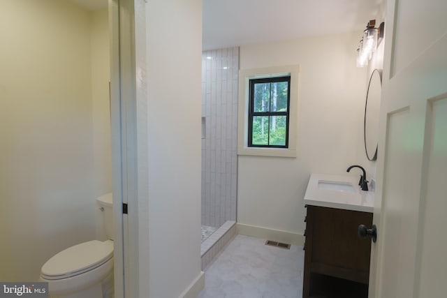 bathroom featuring tile patterned floors, toilet, tiled shower, and vanity