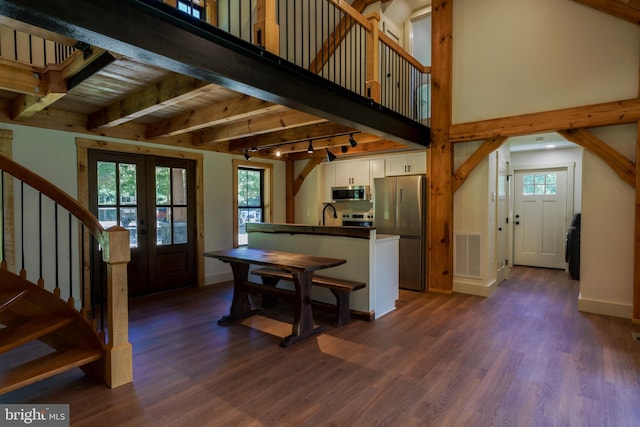 kitchen featuring beamed ceiling, white cabinetry, dark hardwood / wood-style floors, appliances with stainless steel finishes, and track lighting