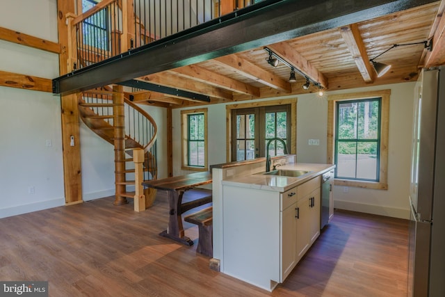 kitchen with beam ceiling, sink, stainless steel appliances, hardwood / wood-style flooring, and white cabinetry