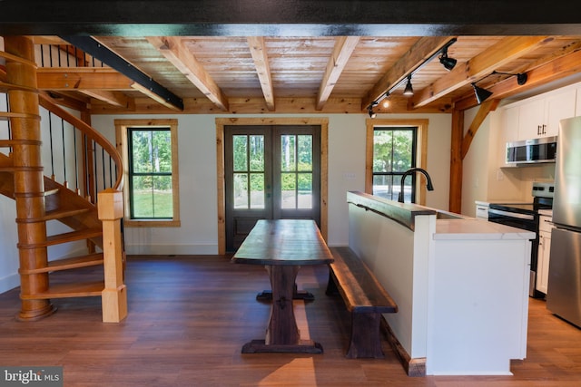 interior space with a kitchen island with sink, a healthy amount of sunlight, stainless steel appliances, french doors, and white cabinets