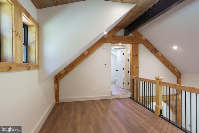 bonus room with wood-type flooring and vaulted ceiling with beams