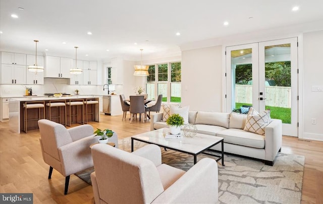 living room with light wood-type flooring, sink, and french doors