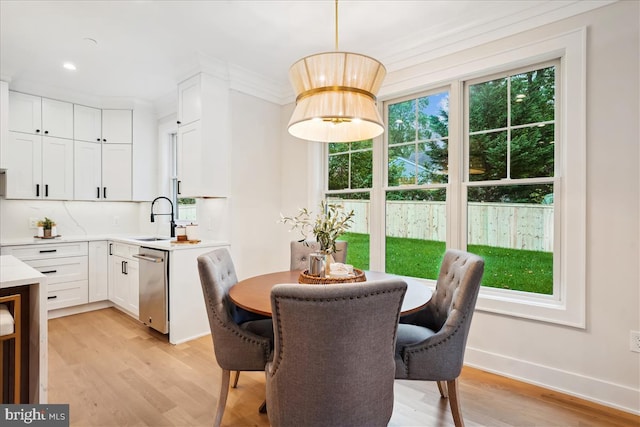 dining room with ornamental molding, light wood-type flooring, and sink