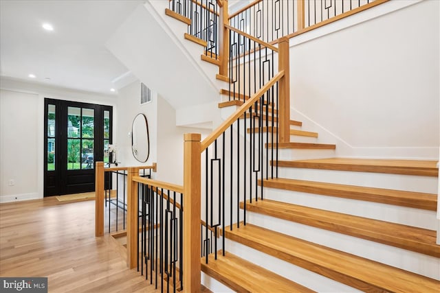 stairs with ornamental molding and hardwood / wood-style flooring