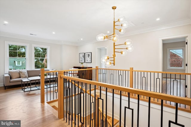 corridor featuring an inviting chandelier, light wood-type flooring, and ornamental molding