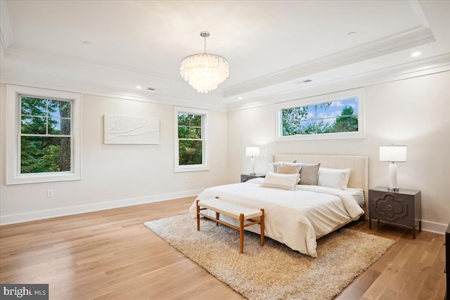 bedroom featuring an inviting chandelier, light wood-type flooring, multiple windows, and a raised ceiling