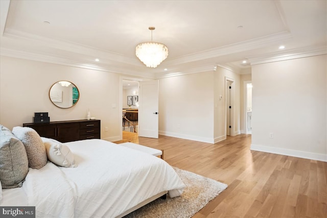 bedroom with a notable chandelier, light wood-type flooring, a raised ceiling, and crown molding