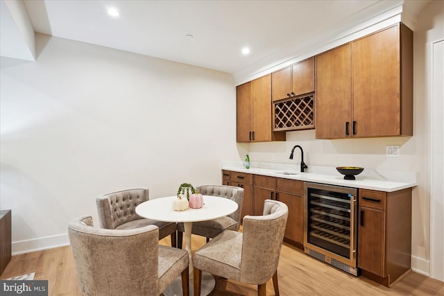 bar featuring beverage cooler, light wood-type flooring, and sink