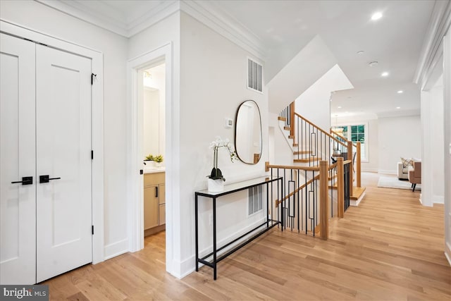 hallway with light wood-type flooring and ornamental molding