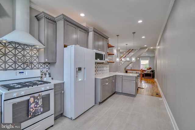 kitchen featuring decorative backsplash, ornamental molding, white appliances, and wall chimney range hood