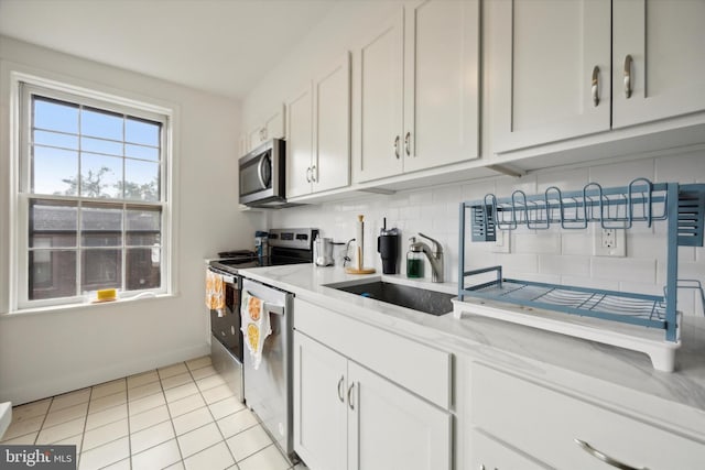 kitchen featuring stainless steel appliances, white cabinets, sink, and light tile patterned floors