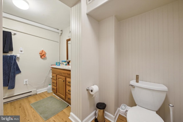 bathroom with hardwood / wood-style floors, a baseboard heating unit, vanity, and toilet