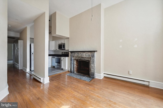 unfurnished living room featuring a premium fireplace, a baseboard heating unit, and light hardwood / wood-style flooring