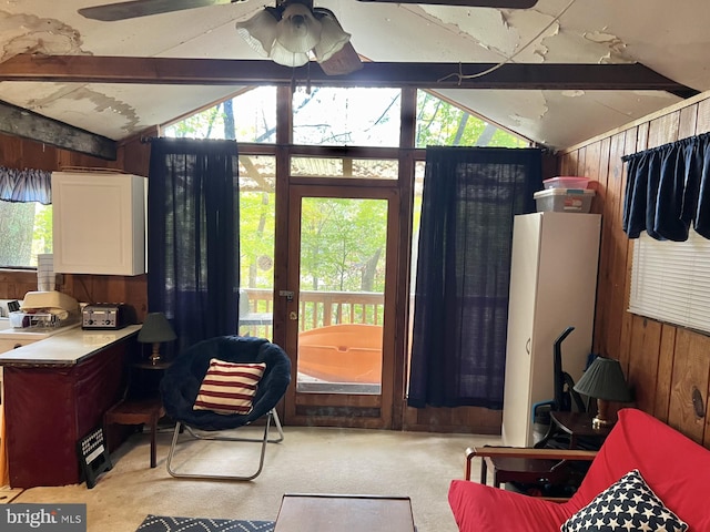 interior space with lofted ceiling with beams, wooden walls, and ceiling fan