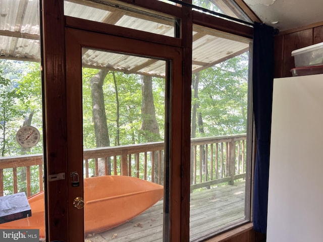 doorway to outside featuring wooden walls and a wealth of natural light