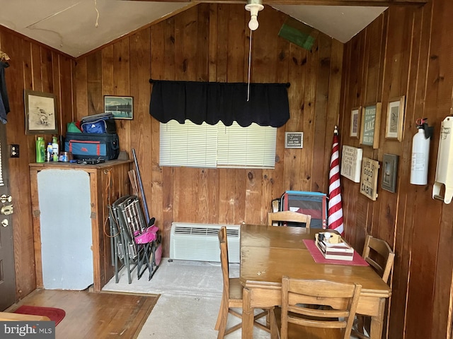 carpeted dining room featuring wood walls and vaulted ceiling