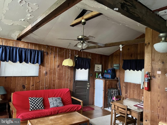 living room with lofted ceiling with beams, wooden walls, and ceiling fan