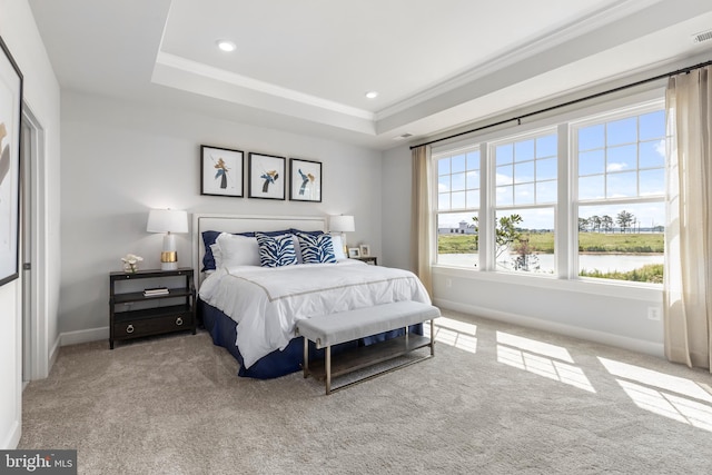 bedroom featuring light colored carpet, a raised ceiling, crown molding, and a water view