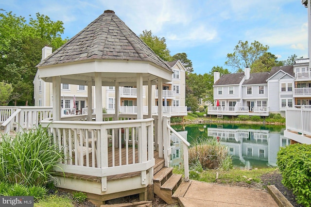 back of property with a water view and a gazebo