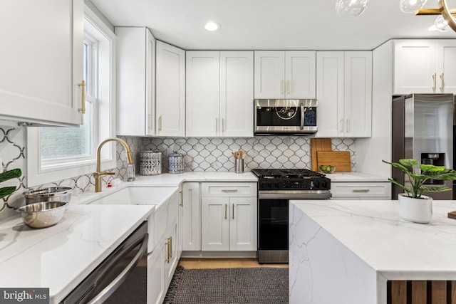 kitchen featuring appliances with stainless steel finishes, white cabinets, light stone countertops, and tasteful backsplash