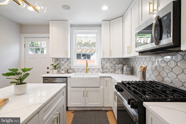 kitchen with white cabinetry, light stone counters, stainless steel appliances, and tasteful backsplash