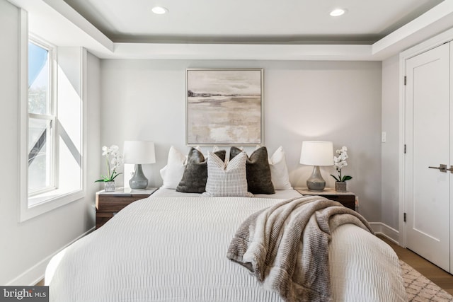 bedroom featuring a tray ceiling and wood-type flooring