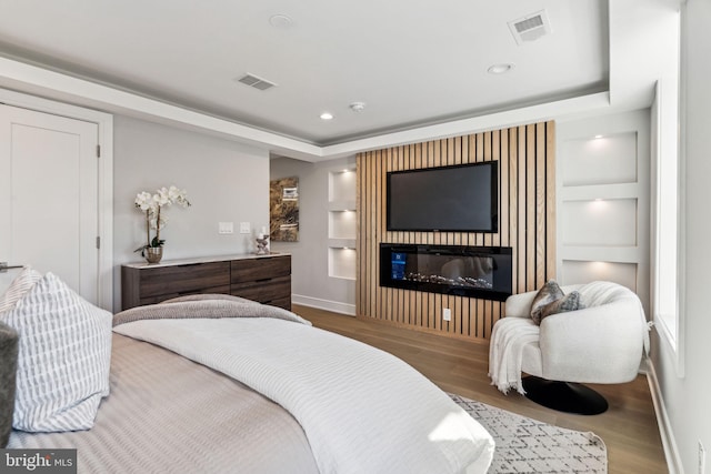 bedroom with wood-type flooring and a raised ceiling