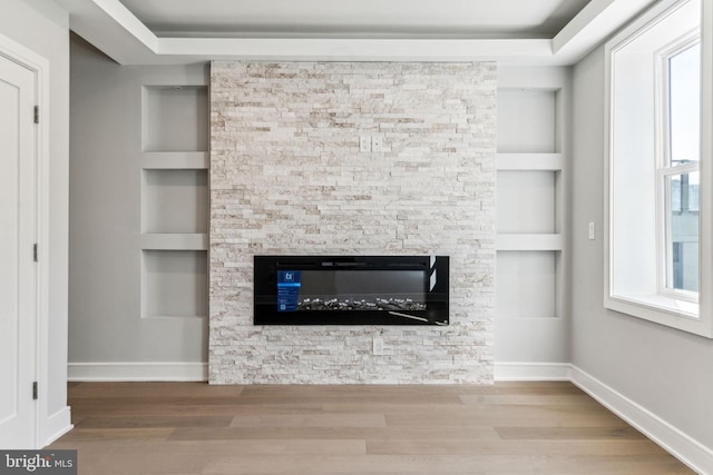 interior details featuring hardwood / wood-style floors, a stone fireplace, and built in features