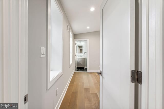 hallway with lofted ceiling and light wood-type flooring