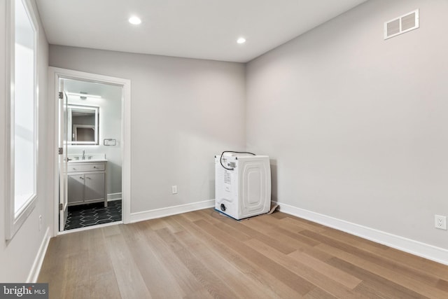 empty room with sink, lofted ceiling, and light hardwood / wood-style flooring