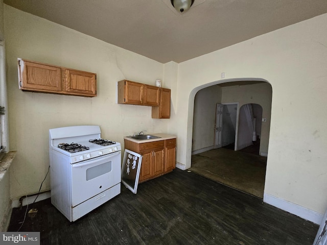 kitchen featuring white gas range, sink, and dark wood-type flooring