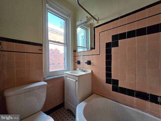 bathroom featuring vanity, tile walls, toilet, and a bath