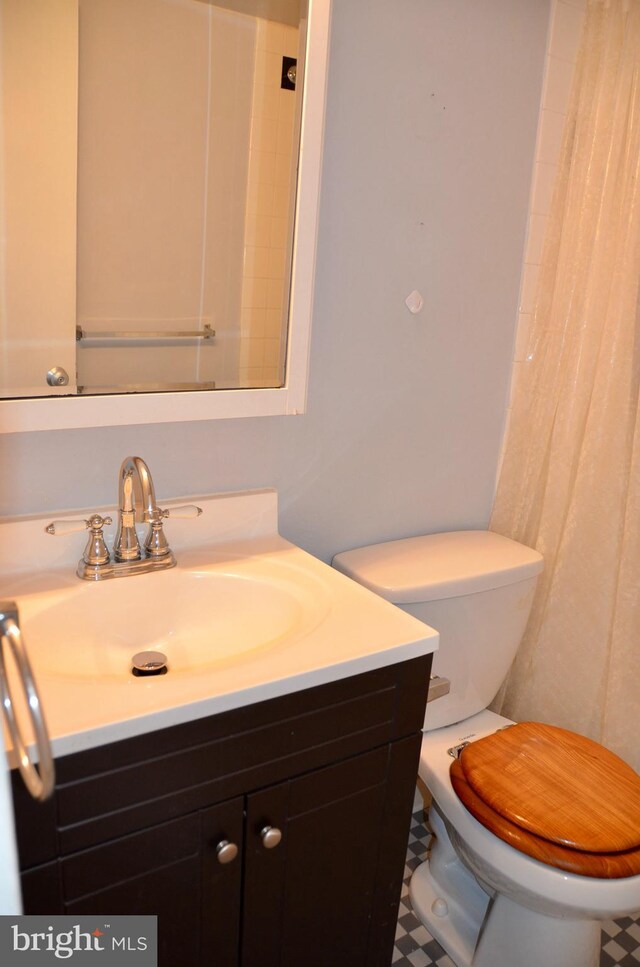 bathroom featuring toilet, curtained shower, and vanity