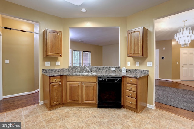 kitchen featuring dark stone countertops, black dishwasher, light wood-type flooring, sink, and a chandelier