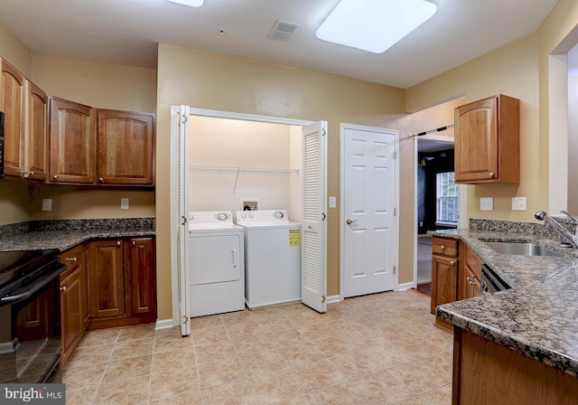 kitchen featuring separate washer and dryer, black / electric stove, dark stone countertops, and sink