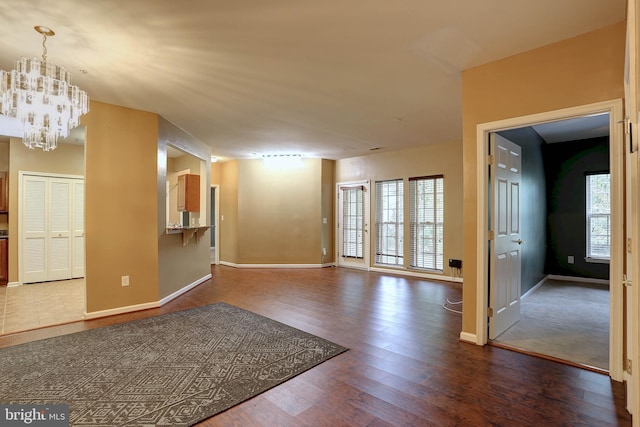 unfurnished room with a notable chandelier and dark wood-type flooring