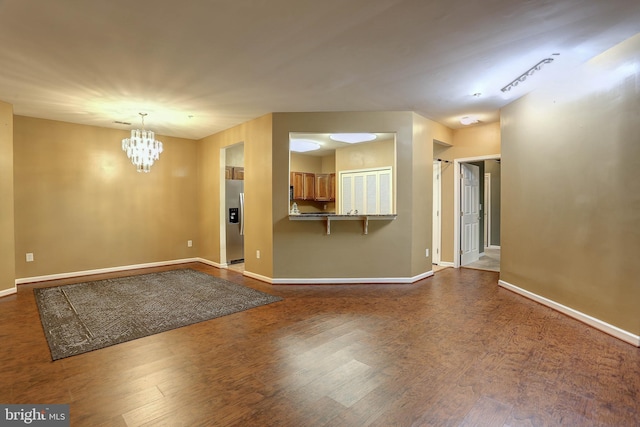 spare room featuring an inviting chandelier and dark hardwood / wood-style floors