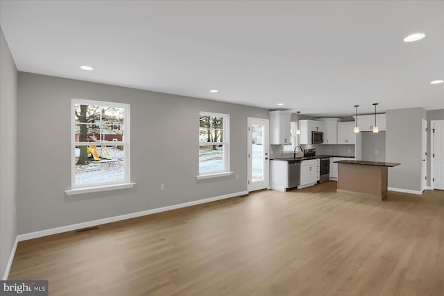 kitchen featuring sink, decorative light fixtures, white cabinetry, and light hardwood / wood-style flooring