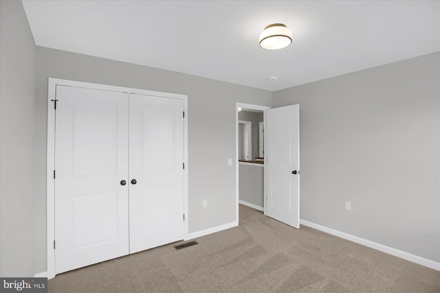 unfurnished bedroom with light carpet and a closet