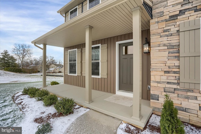 snow covered property entrance with a porch