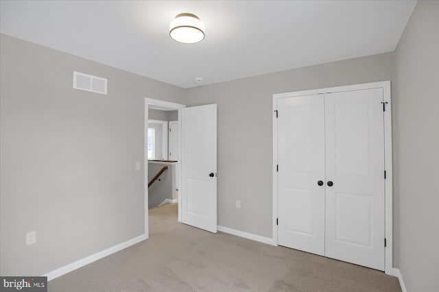 unfurnished bedroom with light carpet and a closet