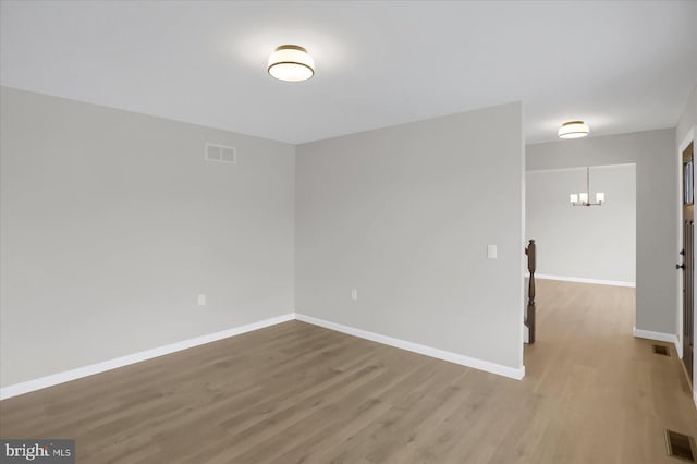 unfurnished room featuring hardwood / wood-style floors and an inviting chandelier