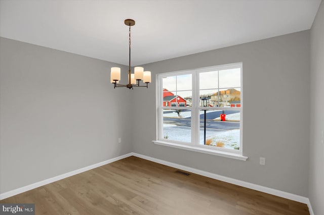 unfurnished dining area with wood-type flooring and a chandelier