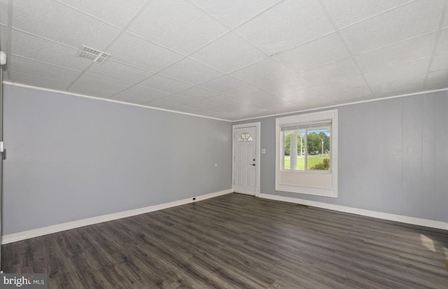 empty room with a paneled ceiling and dark wood-type flooring