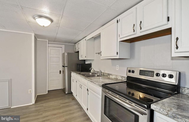 kitchen featuring sink, hardwood / wood-style floors, electric range, and white cabinetry