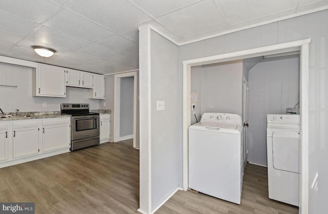 kitchen with a paneled ceiling, white cabinetry, electric stove, separate washer and dryer, and light hardwood / wood-style floors