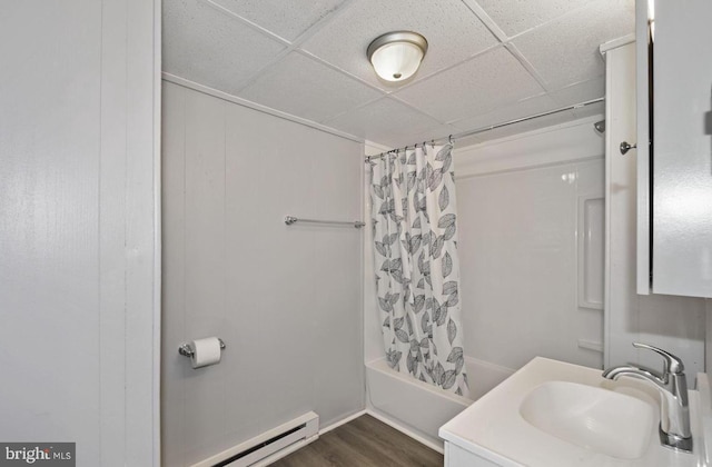 bathroom with shower / bath combination with curtain, wood-type flooring, a baseboard radiator, and a paneled ceiling